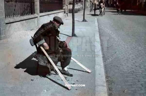 French homeless person begging on street, only one leg with wooden crutches, horse wagon, Paris, France, 1940.