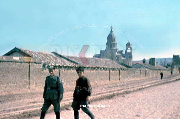 German army soldier walking with Russian Cossack in uniform and boots. Ukraine village 1942