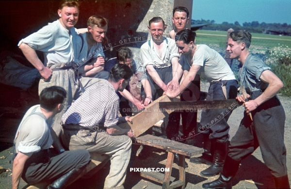 German Luftwaffe air force soldiers cutting wood with long timber saw. Bomber plane Air field. France 1940