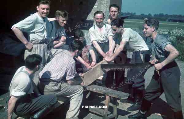 German Luftwaffe Ground crew build staff quarters using large wood saw beside air base landing strip, summer 1941.