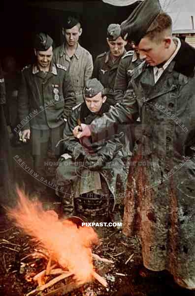 German Luftwaffe motorbike messenger rests with soldiers beside open fire, Russia 1942.