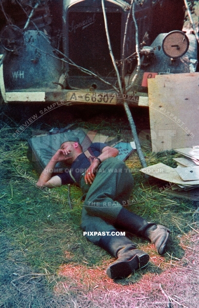 German soldier sleeping beside army Opel truck. Painting road traffic signs. Russia 1942. A-66307