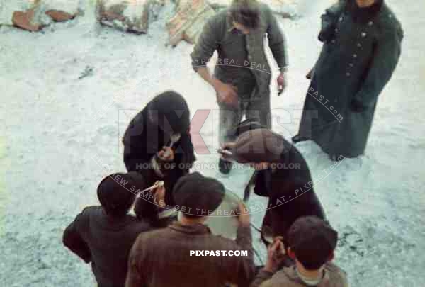 Jewish Forced labour eating on a Starvation Diet in Polish Ghetto. Winter 1942. German police guard watches.