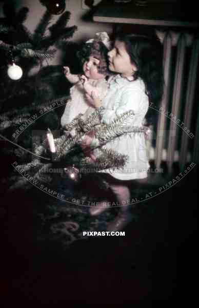 little girl with doll looking at the christmas tree, Germany 1938