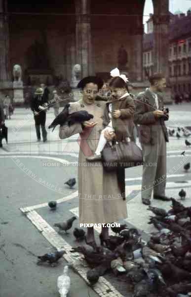 Mother feeding birds with daughter in Odeonsplatz in Munich, Germany 1938, behind Feldherrnhalle,