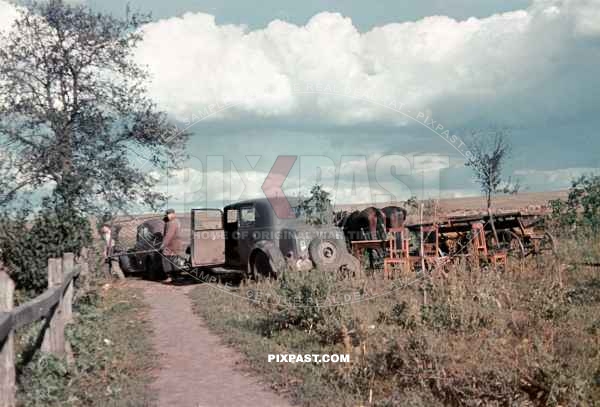 Russian farmers unloading a bed from a german army officers staff car. Russian front summer 1941.