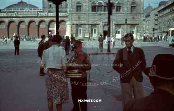 Ticket seller outside front of Munich Main Train Station, Germany. 1940. Tram driving down Arnulfstrasse