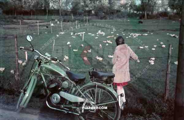 woman in red skirt and leather helmet with a motorbike watching ducks in Bremerhaven, Germany 1939