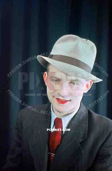 Young Austrian man in American style 20s hat and jacket with red lipstick, theatre show 1937, Later becomes war reporter.